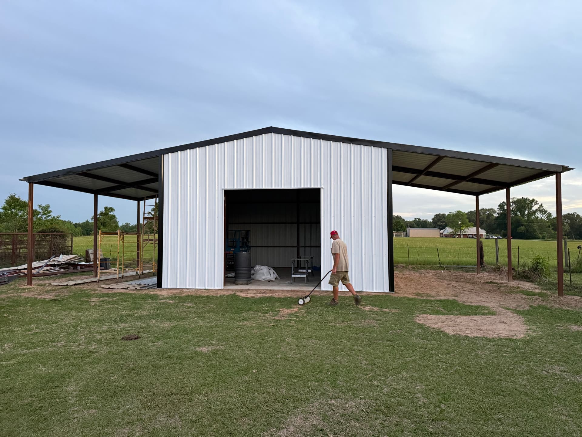 Finished white metal shop building with black trim and covered lean-to awnings