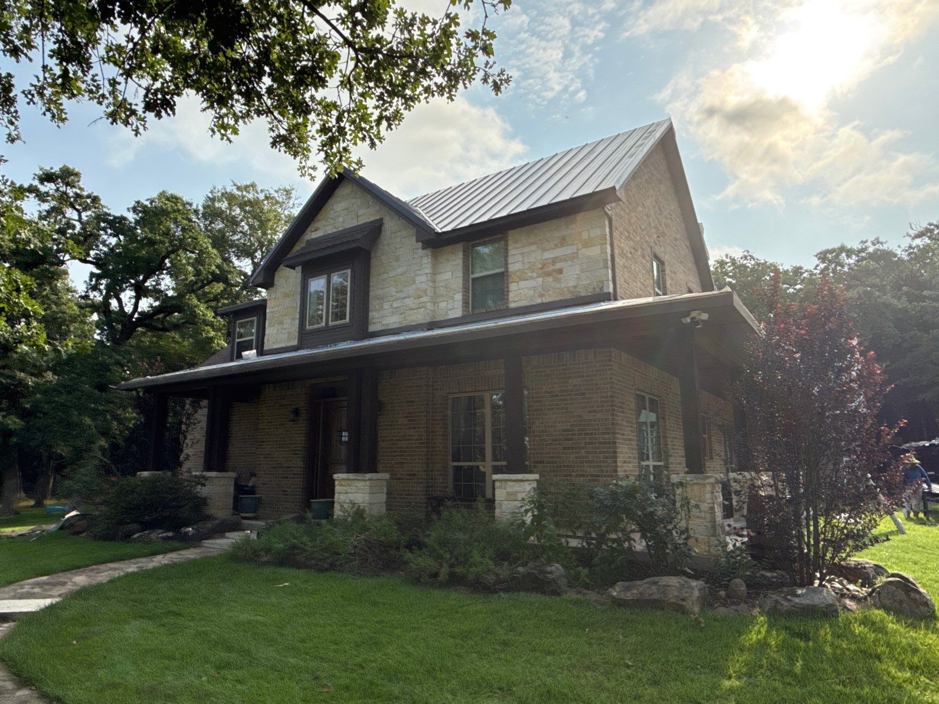Two-story stone home in East Texas with a finished standing seam metal roof