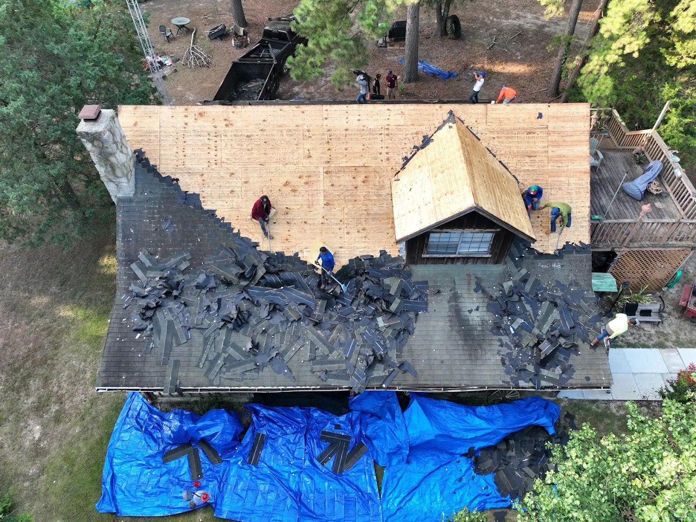 Aerial view of the Calvary Roofing crew tearing shingles off an East Texas home down to the decking