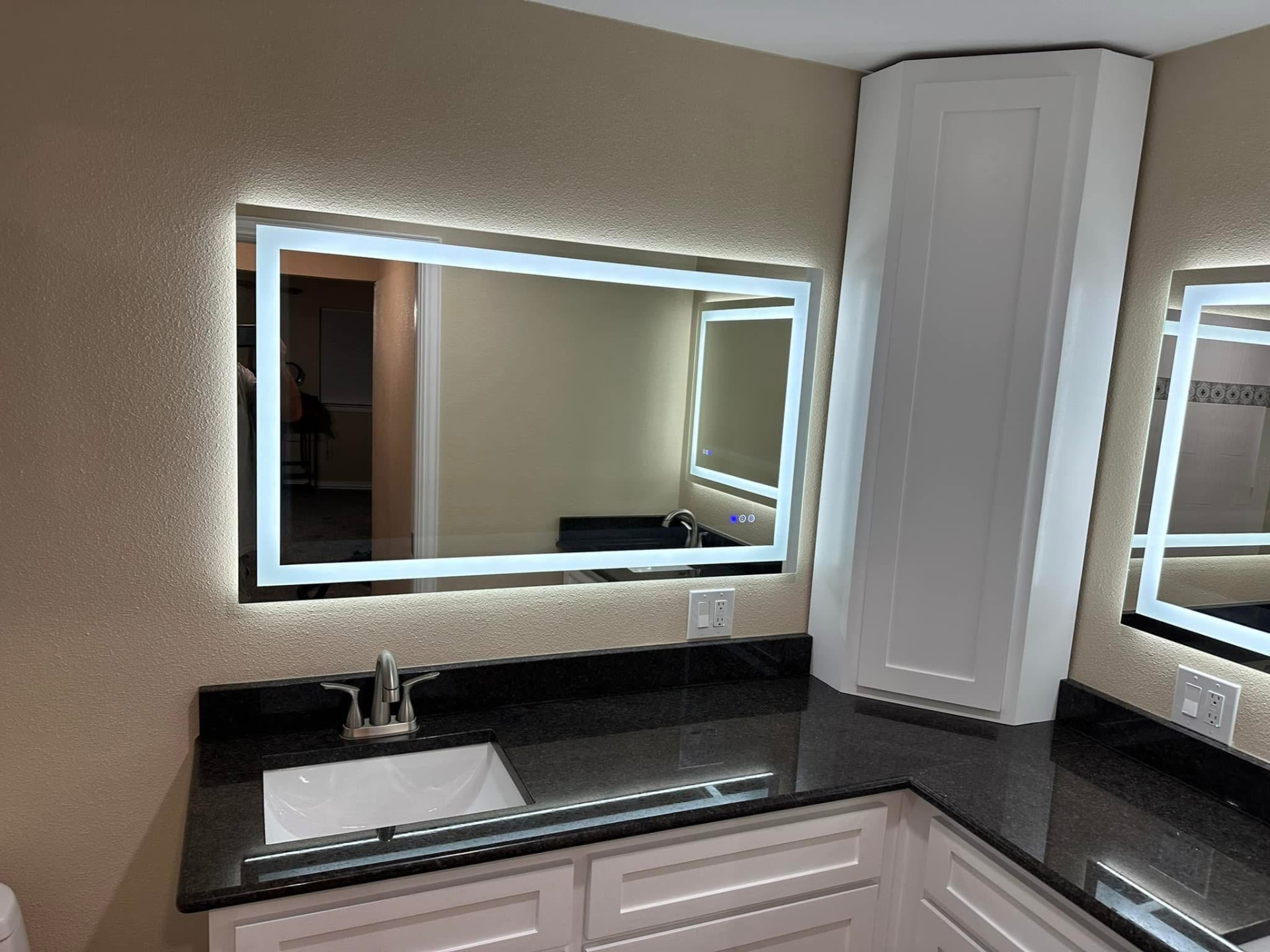 Remodeled bathroom with a white shaker vanity, granite top, and LED mirror